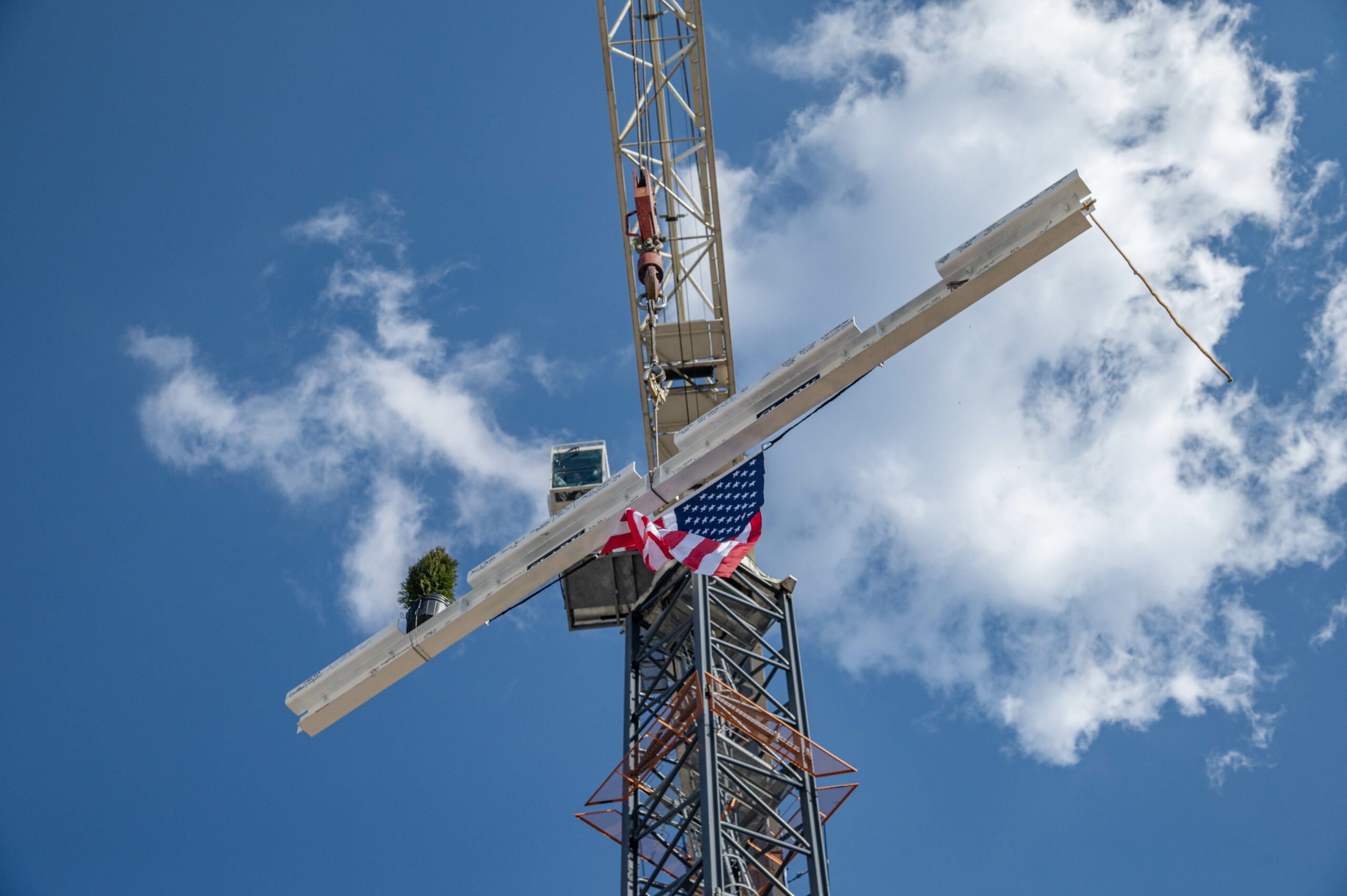 A steel beam hoisted up into the air by a construction crane.